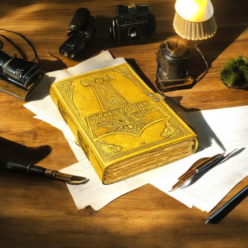 May include: A detailed, yellow leather-bound book with embossed designs and text, featuring a hammer symbol. The book is open on a wooden surface, surrounded by vintage items like a camera, pens, and a small lamp. The scene is lit with warm light.