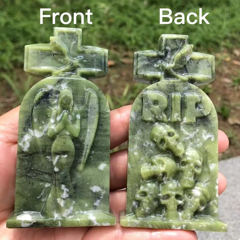 May include: A green stone tombstone with a cross on top. The front features an angel statue, while the back has the letters "RIP" above skulls. The stone has a marbled appearance.