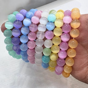 May include: A rainbow-colored bracelet featuring round beads in shades of green, purple, blue, pink, yellow, and orange. The beads are strung together, creating a vibrant and eye-catching accessory. The beads appear to be approximately 0.4 inches in diameter.