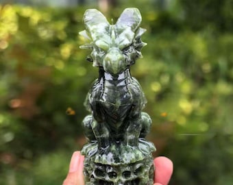 May include: A detailed, green dragon figurine carved from stone. The dragon is seated, with intricate details on its head, body, and base. The sculpture has a polished finish, and the color varies from light to dark green.