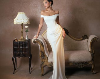 May include: A floor-length white gown featuring an off-the-shoulder neckline, a structured corset-style bodice with vertical seams, and a draped skirt that falls to the floor. The garment is made of a smooth, solid white fabric with a subtle sheen.