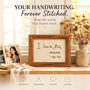 Könnte beinhalten: Ein rechteckiger Holzrahmen mit einer hellen Stoffbespannung, auf der der braune Text I love You, mama, xo xo gestickt ist. Der Rahmen steht neben einem Fotorahmen und einer gesprenkelten Vase mit getrockneten Blumen.