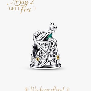 May include: A silver charm depicting a seated figure with a green accent, possibly a fairy, atop a decorative base with star-shaped embellishments. The charm has intricate details and is likely made of sterling silver. The text "Buy 2 Get 1 Free" is in the upper left corner.