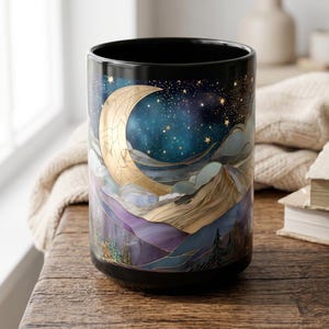 May include: A black ceramic mug featuring a wrap-around illustration of a golden crescent moon, a starry night sky, layered mountain ranges in shades of purple and blue, and a forest of pine trees at the base, all rendered with fine gold lines.