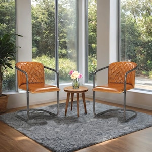 Puede incluir: Dos sillas de cuero marrón con costuras de diamante y marcos de metal oscuro están colocadas sobre una alfombra gris. Una pequeña mesa auxiliar de madera con un jarrón de flores se encuentra entre las sillas. Grandes ventanas ofrecen vistas al exterior.