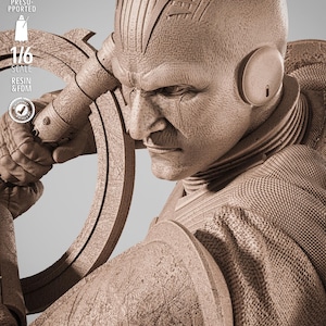 May include: A detailed sepia-toned sculpture of a stern-faced figure with a distinctive head design and ear pieces. The figure is holding a circular object. The image includes text that reads "TESTED PRESUPPORTED", "1/6 SCALE", and "RESIN & FDM".