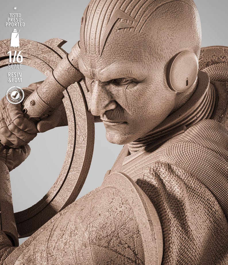 May include: A detailed sepia-toned sculpture of a stern-faced figure with a distinctive head design and ear pieces. The figure is holding a circular object. The image includes text that reads "TESTED PRESUPPORTED", "1/6 SCALE", and "RESIN & FDM".