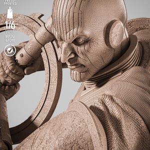 May include: A detailed, sepia-toned sculpture of a stern-faced humanoid figure, holding a circular object. The figure has textured skin and is wearing a detailed costume. The image includes text indicating a 1/6 scale and resin/FDM material.