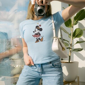 Puede incluir: Una taza de cer&aacute;mica blanca con un asa negra y el texto "But First, Coffee" en negrita negra. La taza est&aacute; sobre una superficie de madera. La taza mide aproximadamente 10 cm de alto.