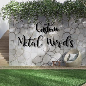 May include: Black metal words spelling "Custom Metal Words" are mounted on a stone wall. The words are in a cursive font. The wall is part of an outdoor scene with a wooden deck, grass, and a wicker chair.