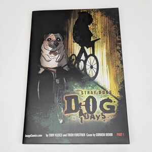 May include: Comic book cover with a pug wearing a saw-like mask, riding a bicycle. The title "STRAY DOGS: DOG DAYS" is visible. The artwork has a dark, gritty style with a touch of horror. The comic is part 1.