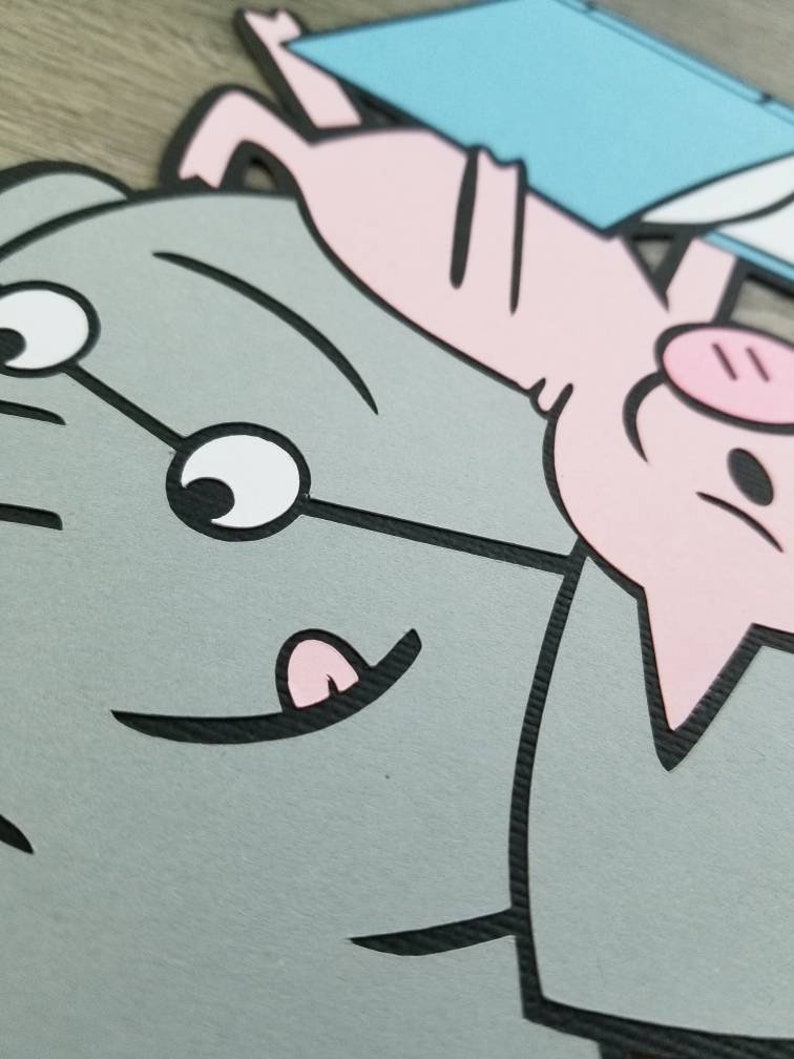 May include: A layered paper cutout featuring a large gray elephant with a smiling expression and a small pink pig positioned above it. The pig is holding a light blue rectangular object. The design uses bold black outlines and flat colors.
