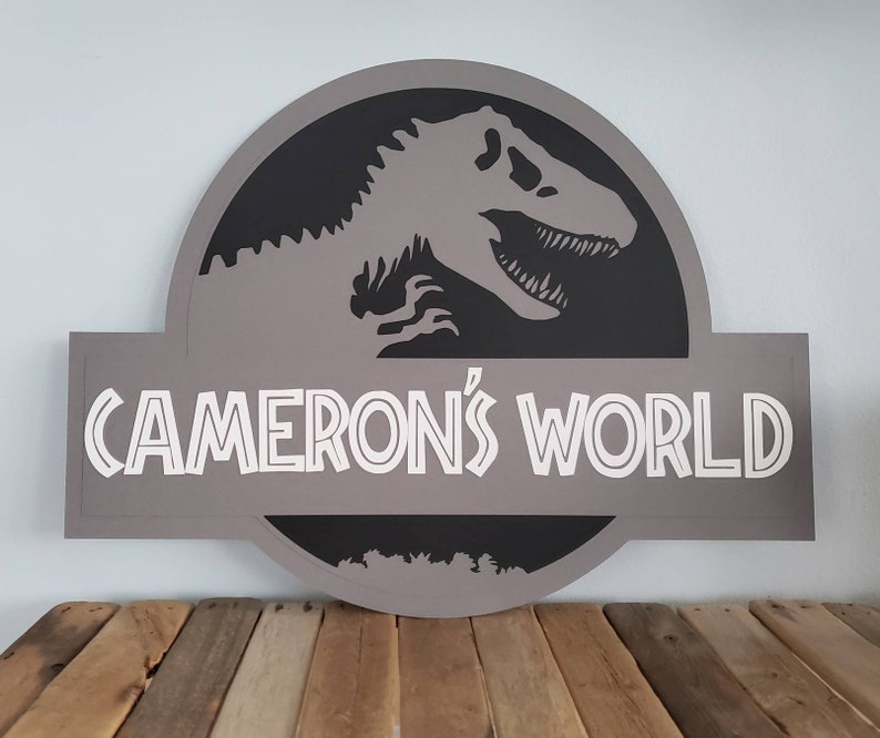 May include: A gray wooden sign with a black silhouette of a dinosaur and the text "CAMERON'S WORLD" in white.