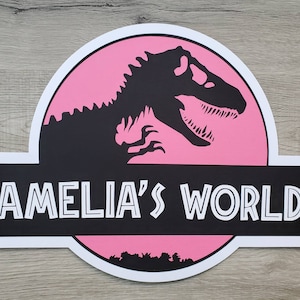 May include: Pink and black sign with a dinosaur silhouette and the text "Amelia's World".