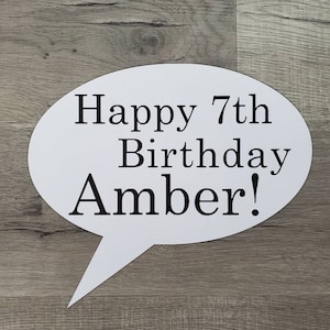 May include: White speech bubble with the text "Happy 7th Birthday Amber!" in black lettering.