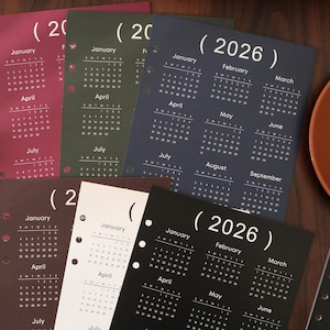 Pu&ograve; includere: Una collezione di pagine di calendario per l'anno 2026 in vari colori, tra cui bordeaux, verde, blu navy, marrone, bianco e nero. Ogni pagina presenta un layout di calendario mensile con il nome del mese e i giorni della settimana.
