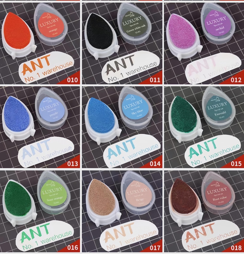 May include: A collection of ink pads in various colors, including orange, black, purple, blue, green, and brown. Each pad is teardrop-shaped and comes with a clear plastic case. The text "LUXURY" and "ANT No. 1 warehouse" are visible.