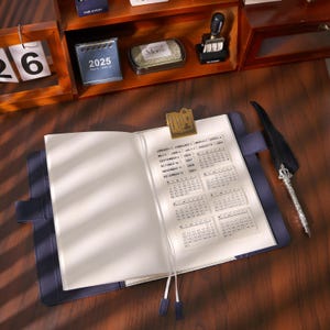 May include: Open navy blue leather journal with blank pages and a gold-colored bookmark. The journal is open on a wooden desk, with a calendar overlay and a decorative pen with a feather. A small 2025 calendar is visible in the background.