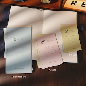 May include: A selection of planner inserts in various sizes, including Personal, A7, and M5. The inserts feature monthly calendars for 2026, with the months of May, and September visible. The pages are in pastel colors, with the text "TWENTY TWENTY-SIX".