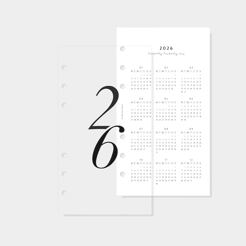 May include: A minimalist planner insert for 2026. The design features a white paper with a calendar layout and the year printed at the top. A transparent overlay with the large numbers "26" is on the left.
