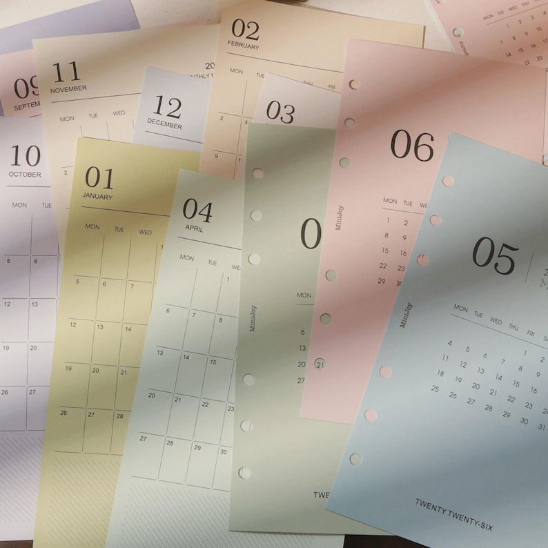 May include: A collection of colorful calendar pages with months and dates visible. The pages are in various pastel colors, including pink, green, and yellow. The calendar pages are for the year 2026.