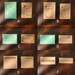 May include: A collection of wooden stamps with various designs, including cats, clocks, and calendars. The stamps are in different shapes and sizes, with some featuring text like "What Should I Do Today?" and "Week Challenge". The color palette includes shades of green and brown.