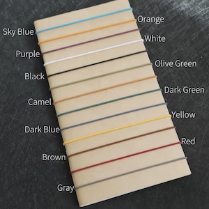 May include: A notebook with various colored cords attached. Colors include sky blue, orange, purple, white, black, olive green, camel, dark green, dark blue, yellow, brown, red, and gray. Text labels each color.