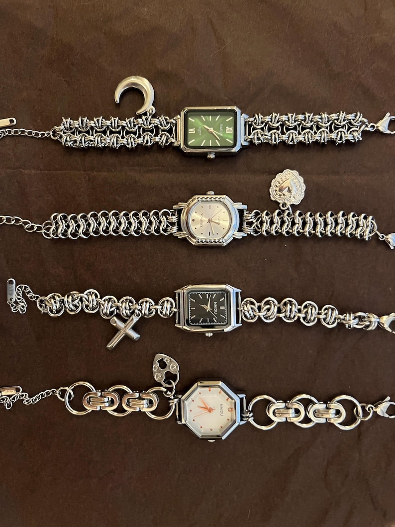 May include: Four silver-toned watches with unique chain-link bands and watch faces. One watch has a green face, another has a black face, and a third has a white face. A silver-toned ear gauge and a charm are also present.