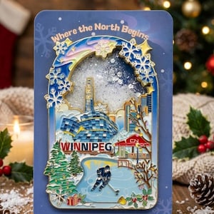 May include: A blue rectangular pin featuring a winter scene of Winnipeg, Canada, with the text "Where the North Begins" and "WINNIPEG". The pin includes a hockey player on a rink, buildings, and snowflakes. The pin is surrounded by a gold border.