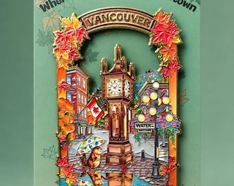 May include: A metal enamel pin featuring the Vancouver Gastown steam clock, surrounded by autumn maple leaves. The pin displays the text "Where Leaves Settle in Gastown", "VANCOUVER", and "WATER ST GASTOWN". A small beaver with a colourful umbrella stands nearby.
