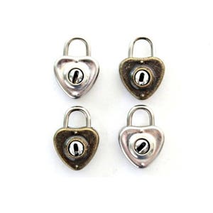 May include: Four heart-shaped padlocks in silver and bronze tones are arranged on a white background. Each padlock has a keyhole and a curved handle. The locks are likely used for jewelry or craft projects.