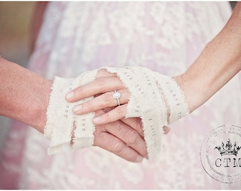 May include: Two hands are tied together with a white fabric ribbon that has the words "I love you" printed on it. The woman's hand is wearing a diamond engagement ring.