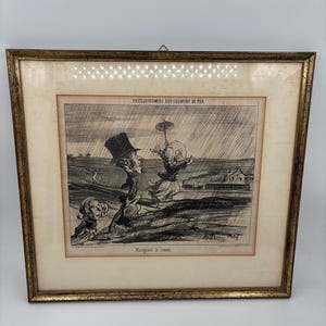 May include: Framed antique print with a gold-colored frame. The black and white illustration depicts caricatures of figures in a rainy landscape. Text at the top reads "PHYSIOGNIES DES CHEMINS DE FER" and "Manquant le convoi" at the bottom.