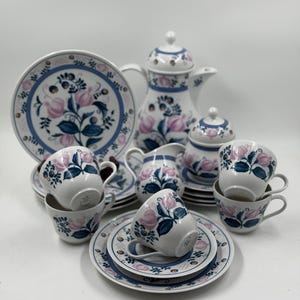 Può includere: Un servizio da tè vintage completo con un design floreale con accenti rosa e blu. Il set include una teiera, una lattiera, una zuccheriera, tazze e piattini. I piatti e le tazze hanno un bordo blu.