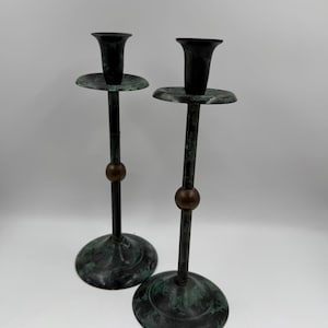 Puede incluir: Una taza de cerámica blanca con un asa negra y el texto "But First, Coffee" en negrita negra. La taza se encuentra sobre un fondo neutro, resaltando su diseño sencillo.