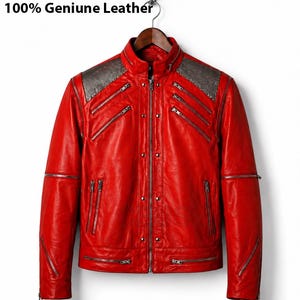 May include: A vibrant red leather jacket with multiple silver zippers and studded shoulder accents. The jacket features a stand-up collar and is hanging on a wooden hanger. The text "100% Genuine Leather" is visible at the top.