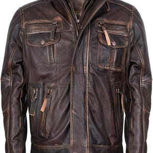 Op de afbeelding: Bruine leren jas met een distressed afwerking. Voorzien van een opstaande kraag, meerdere zakken met ritssluiting en een ritssluiting aan de voorkant. De jas heeft een vintage, versleten uitstraling, met zichtbare slijtplekken en een getextureerd oppervlak. De kraag is geribbeld.
