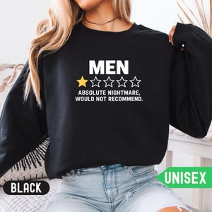 May include: A black long-sleeve sweatshirt featuring the white text MEN above a five-star rating graphic with one yellow star and four white outlined stars, followed by the white text ABSOLUTE NIGHTMARE, WOULD NOT RECOMMEND.