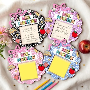 May include: Four teacher appreciation gifts with a notebook paper design. Each frame has a bow, flowers, and a space for a photo or note. The frames are in black, purple, pink, and blue, with text that reads "Mrs. Christine" and "Mrs. Madison."