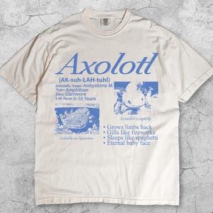 May include: Cream-coloured t-shirt with the word "Axolotl" in blue, plus scientific information and illustrations of the amphibian. The shirt also features the text "Grows limbs back" and "Eternal baby face."