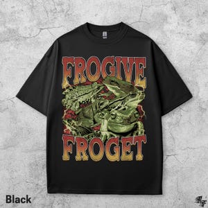 Pu&ograve; includere: T-shirt nero con una grafica di diverse rane verdi e la scritta "FROGIVE FROGET" in un font retr&ograve;. La maglietta &egrave; a girocollo.