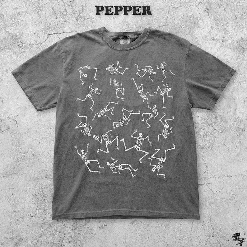 May include: Pepper-colored t-shirt with a white skeleton print. The skeletons are in various poses, creating a dynamic and playful design. The word "PEPPER" is printed at the top of the image. This tee is a unique addition to any wardrobe.
