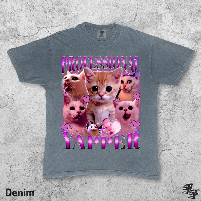 May include: Denim blue t-shirt featuring a graphic of several cats with the text "PROFESSIONAL YAPPER" in a pink and purple font. The cats are in various poses, with hearts around them.