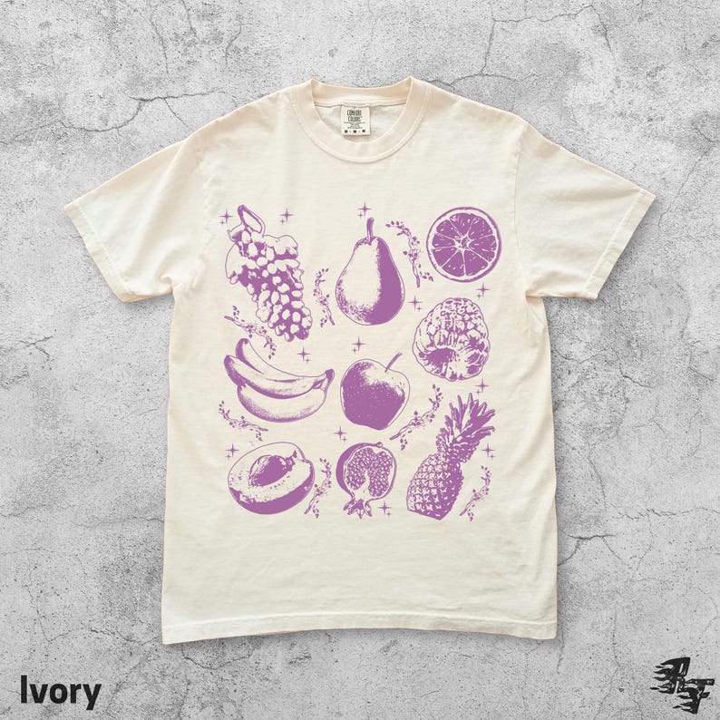 Pu&ograve; includere: T-shirt color avorio con illustrazione di frutta viola: uva, pera, fetta d'arancia, ananas, banane, mela, pesca e melograno. La parola "Ivory" &egrave; stampata in basso.