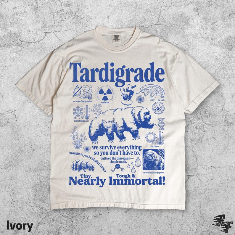 Puede incluir: Una camiseta de manga corta color marfil con un estampado gr&aacute;fico azul de un tard&iacute;grado. El dise&ntilde;o incluye iconos cient&iacute;ficos y el texto Tardigrade, we survive everything so you don't have to, outlived the dinosaurs, simple math y Tiny, Nearly Immortal!