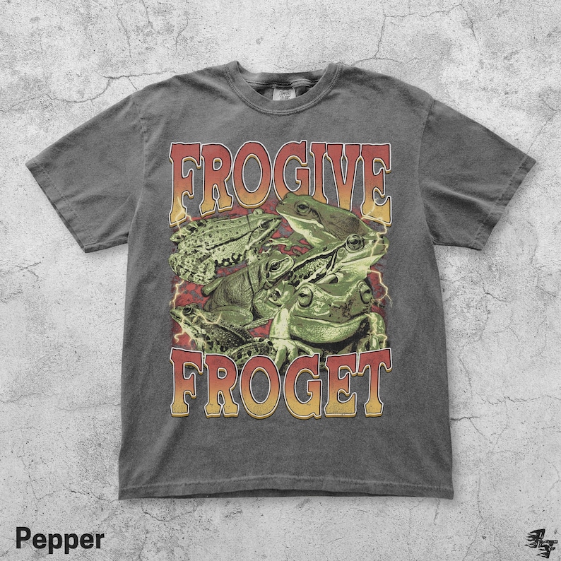 Pu&ograve; includere: T-shirt color pepe con una grafica di diverse rane verdi e la scritta "FROGive FROGet" in un font retr&ograve;. La maglietta ha un aspetto vintage e usurato.
