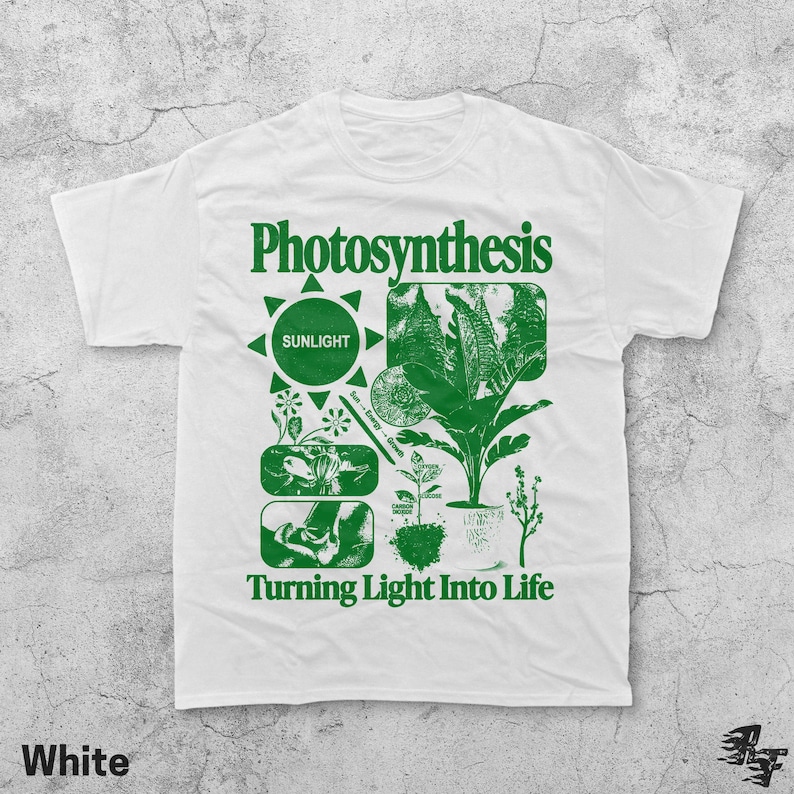 Op de afbeelding: Wit T-shirt met een groen grafisch ontwerp met het woord "Photosynthese" en illustraties van planten, een zon en de tekst "Turning Light Into Life". Het shirt heeft een ronde hals en korte mouwen.