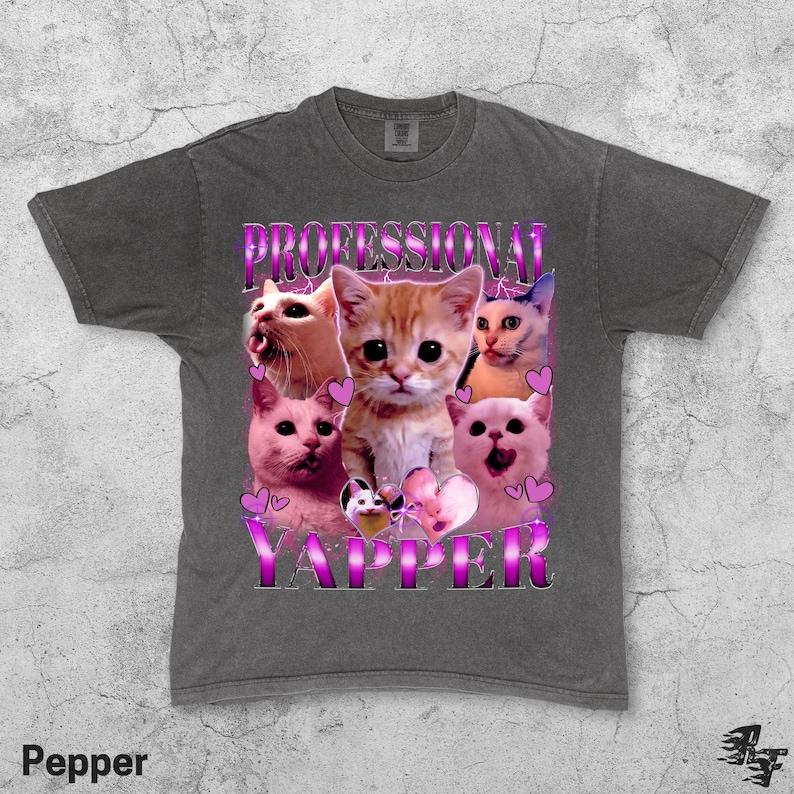 May include: A dark gray t-shirt featuring a collage of cat faces with the text "PROFESSIONAL YAPPER" in a purple, outlined font. The word "Pepper" is printed at the bottom left corner.