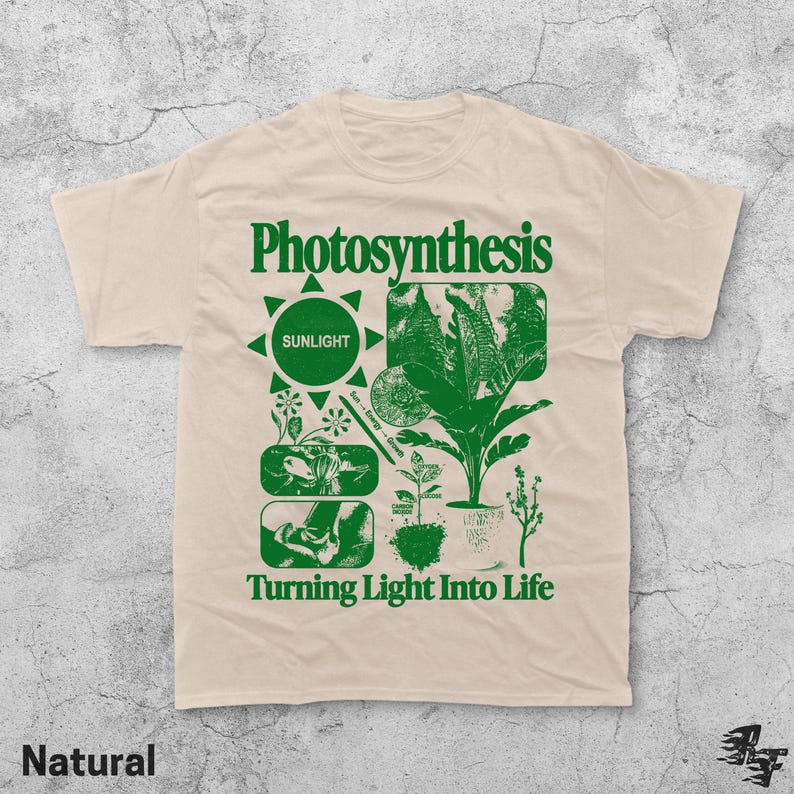 Op de afbeelding: Natuurkleurig t-shirt met een groen grafisch ontwerp. Het ontwerp bevat het woord "Photosynthesis" boven een zon-icoon en botanische illustraties. De tekst "Turning Light Into Life" staat eronder.