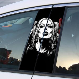 May include: Car window sticker in black and white, depicting a woman with pigtails and makeup blowing a kiss. The image is a pop art style design. The sticker is applied to the car window, with the car's interior visible.